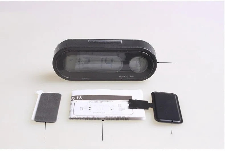 Black digital LED car clock and thermometer with adjustable mounting bracket on a dashboard.