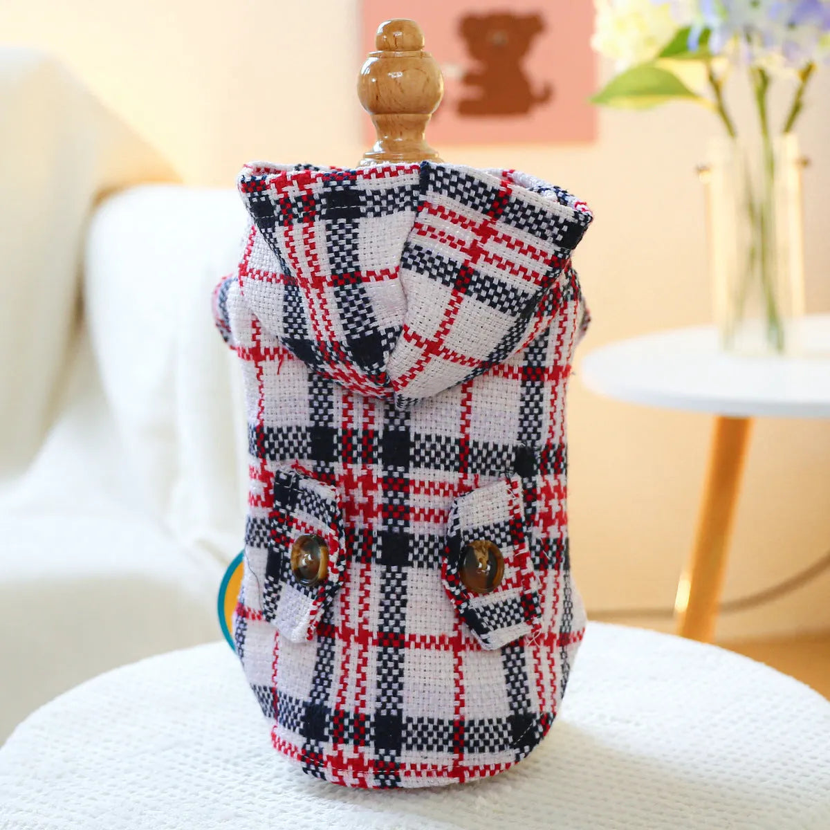 Red plaid trench coat for a dog, shown alongside a black houndstooth version, on a mannequin.