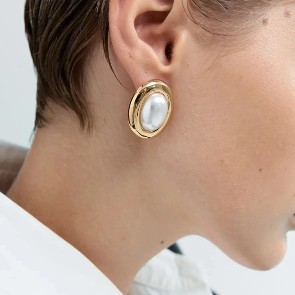 A pair of stainless steel stud earrings with a vintage-style pearl accent in colour JDE0305051.