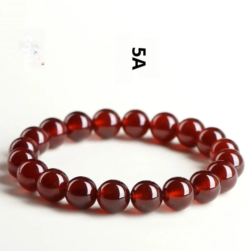 Natural orange red garnet ball bracelet with a traditional Ruyi-style clasp on a wrist.