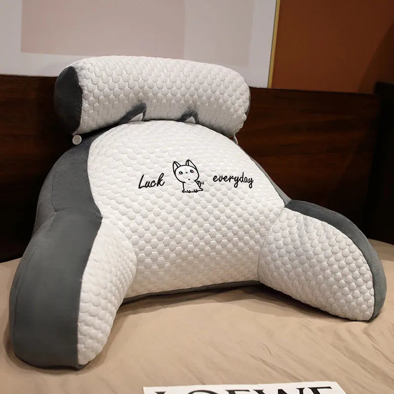 Grey triangle-shaped reading pillow with embroidery on a chair, showing its ergonomic back support shape.