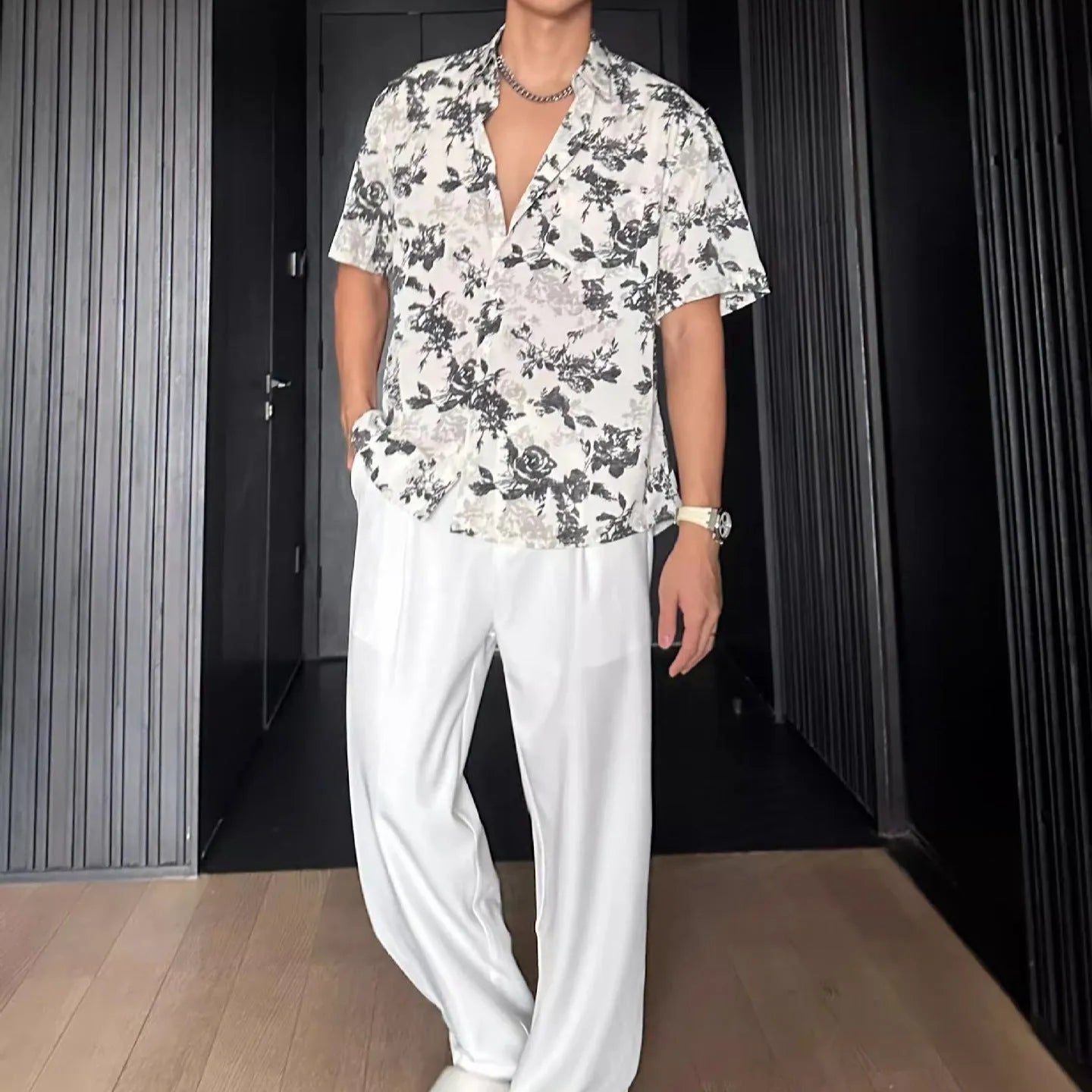 Man wearing a loose black short-sleeve shirt with a floral printed pattern.