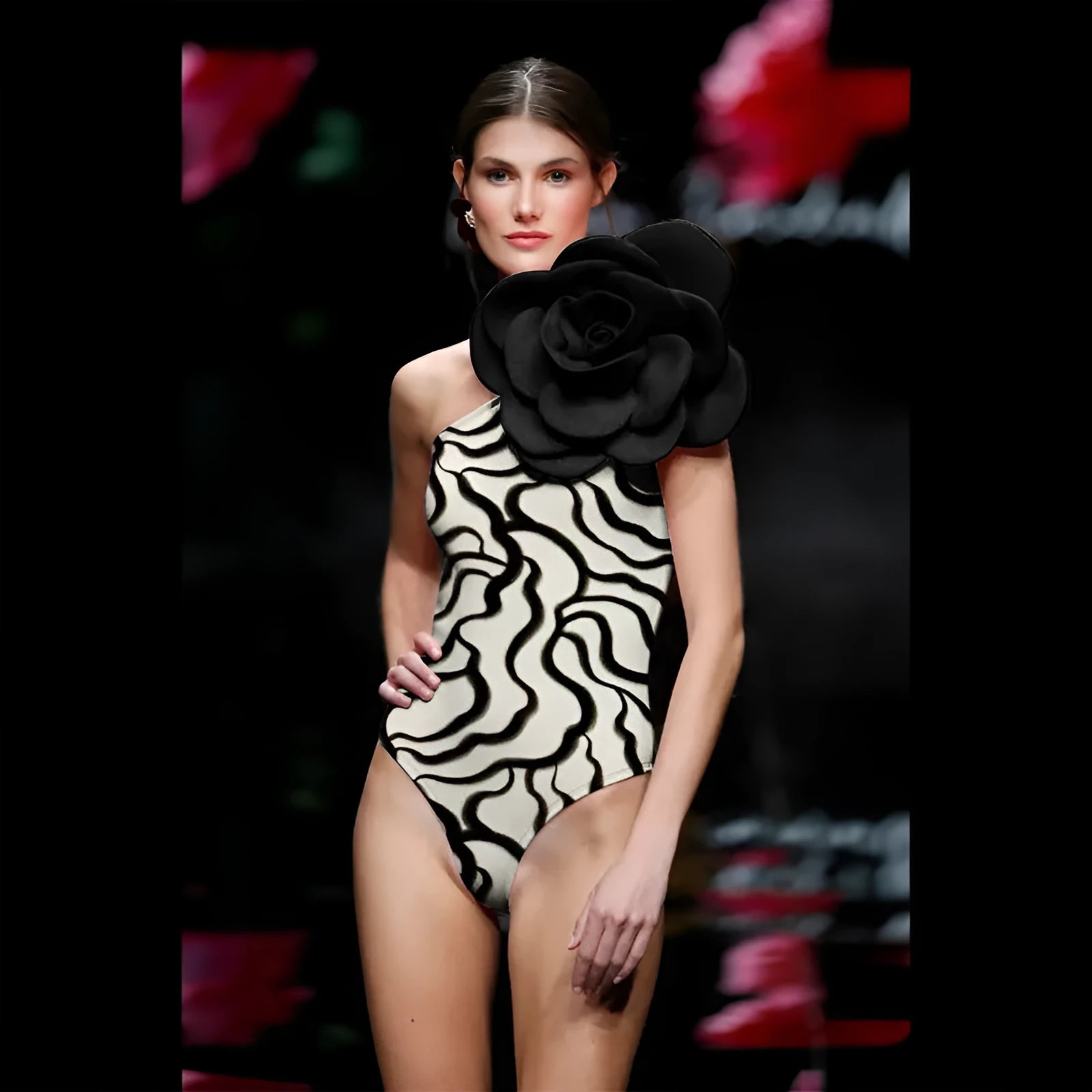 Black one-piece swimsuit with three-dimensional white floral pattern on a mannequin.