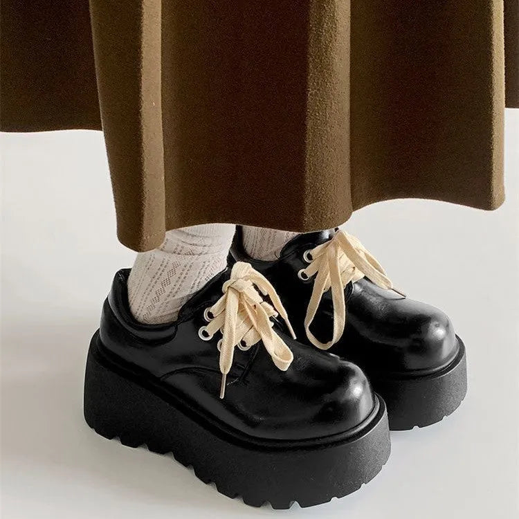 Black women's lace-up heels with a chunky rubber sole and a retro English muffin heel.