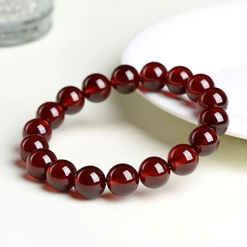 Natural orange red garnet ball bracelet with a traditional Ruyi-style clasp on a wrist.