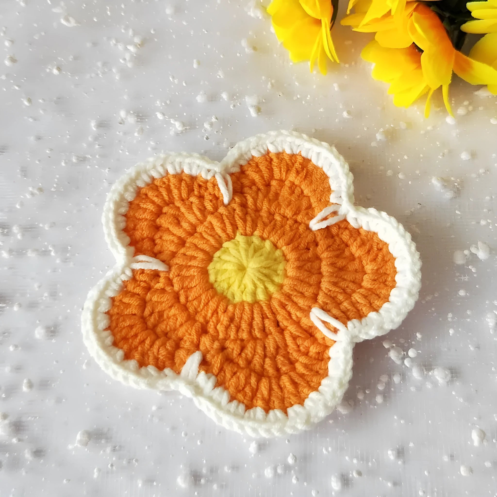 Five handmade woven flower placemats in blue, green, orange, pink and purple colours on a dining table