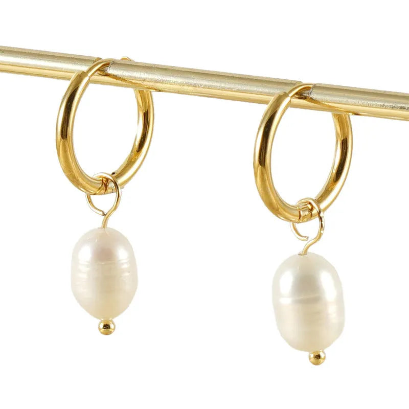 Gold geometric drop earrings with a freshwater pearl detail on a stainless steel setting.