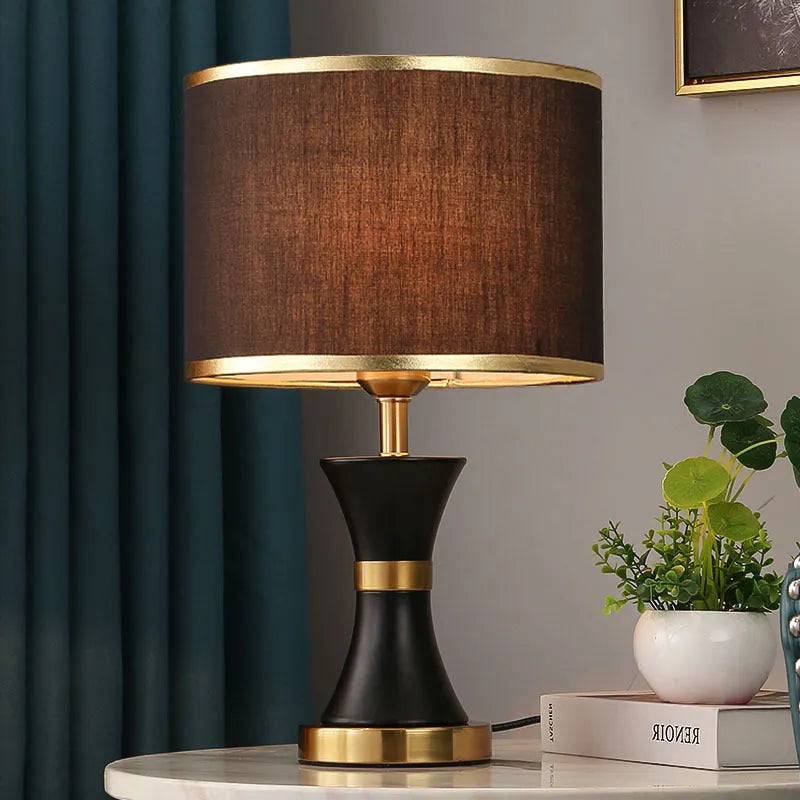 Iron table lamp with cloth shade in black, gold, or white colour on a wooden table