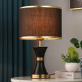 Iron table lamp with cloth shade in black, gold, or white colour on a wooden table