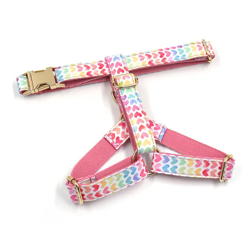 Pink dog harness with colourful heart-shaped stones and a gold-coloured buckle on a white background.