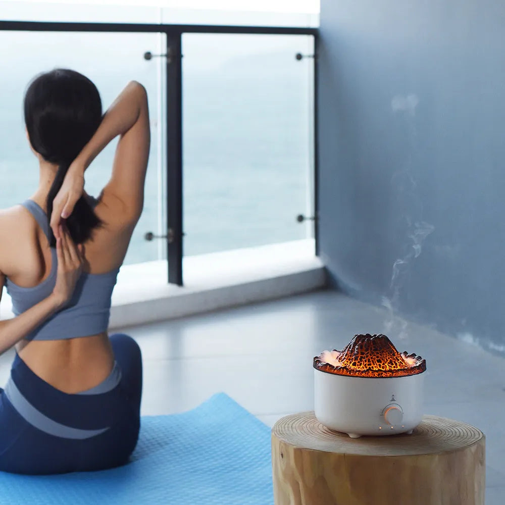 Small white volcano-shaped humidifier with simulated flame lighting and remote control on wooden table