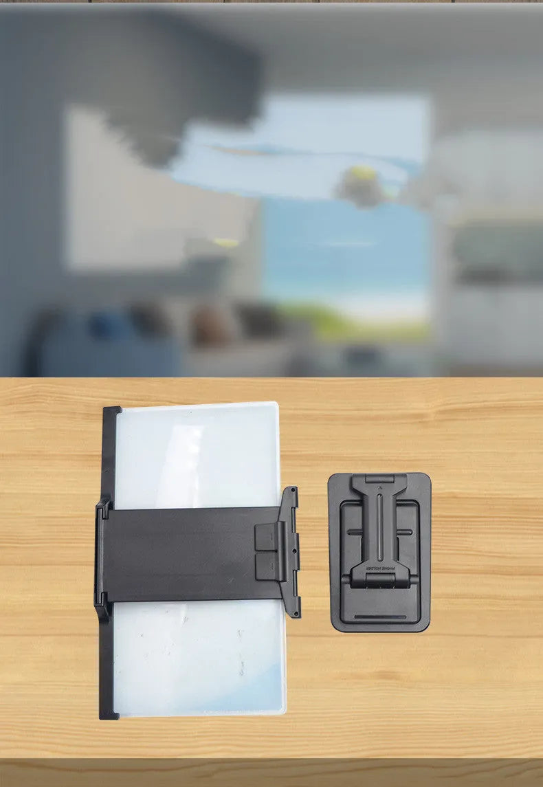 Black folding mobile phone screen amplifier with detachable holder on a desktop.
