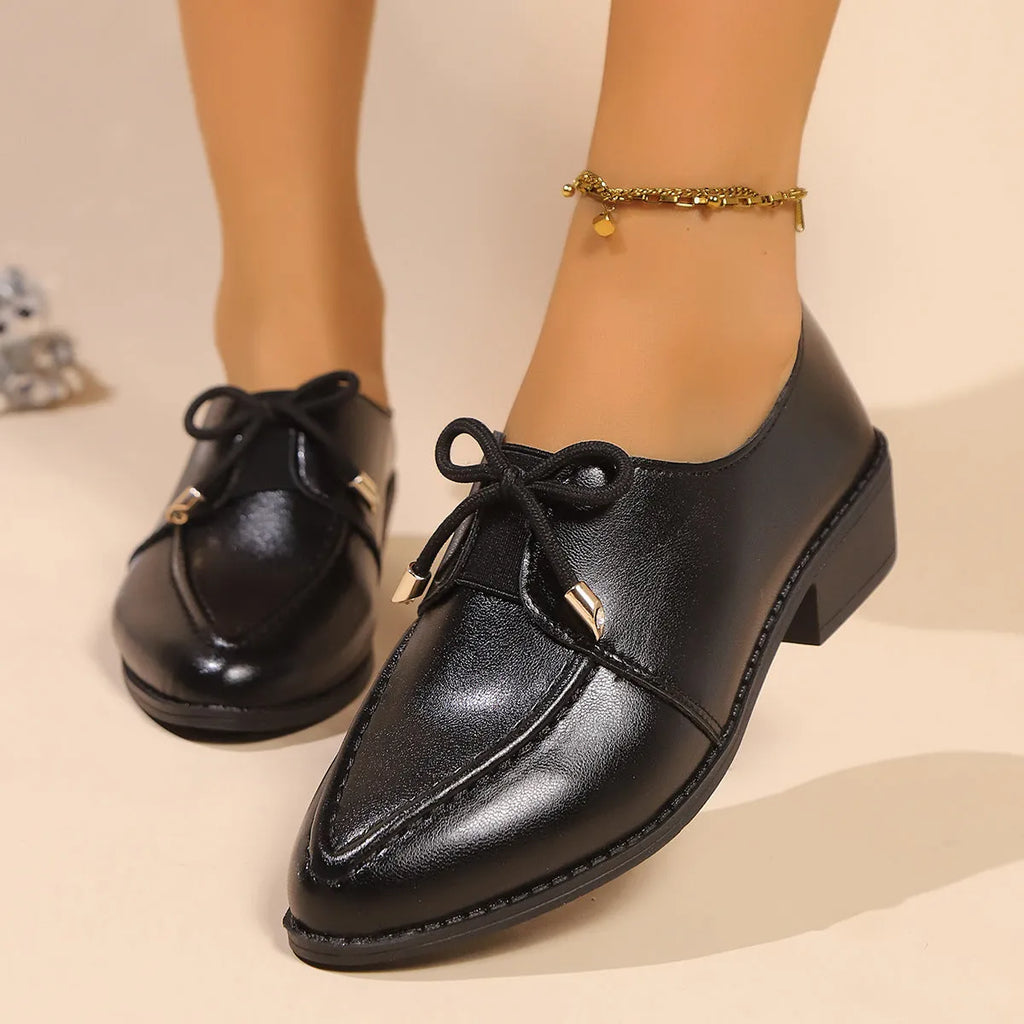 Women's casual leather shoes with a decorative bow on a pointed toe, showcasing a rubber sole.