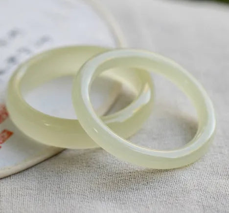Close-up of a smooth, ice-like silk jade round bar bracelet on a wrist.