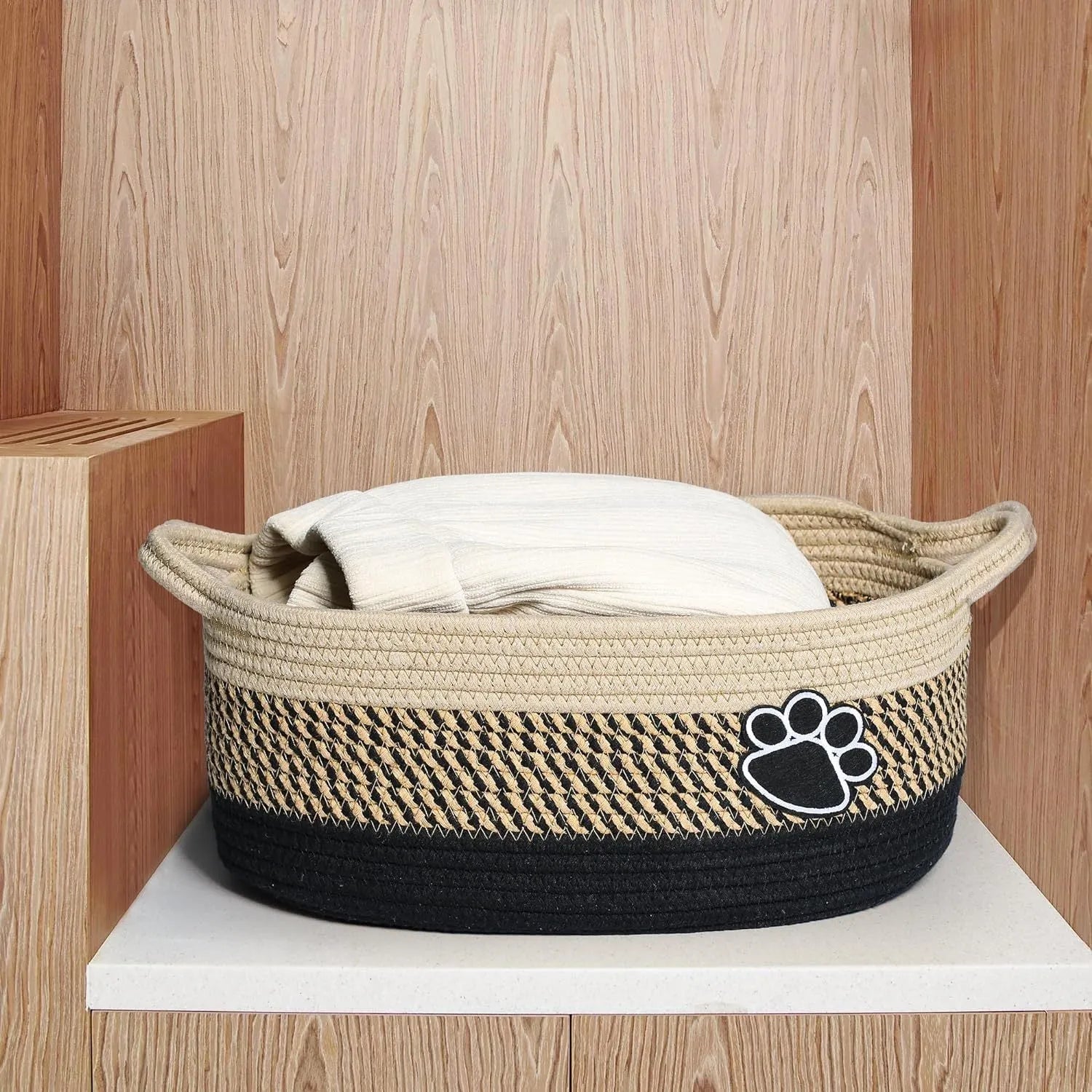 Small light beige woven cotton rope storage basket with a handle on a wooden surface