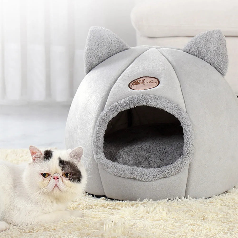 A fully enclosed cube-shaped cat sofa nest, showing the entrance hole, in a home setting.