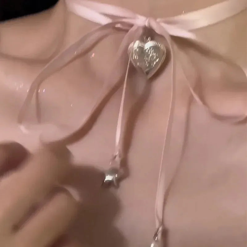 Women's silver-tone alloy necklace with a ribbon-shaped love pendant on a thin chain.