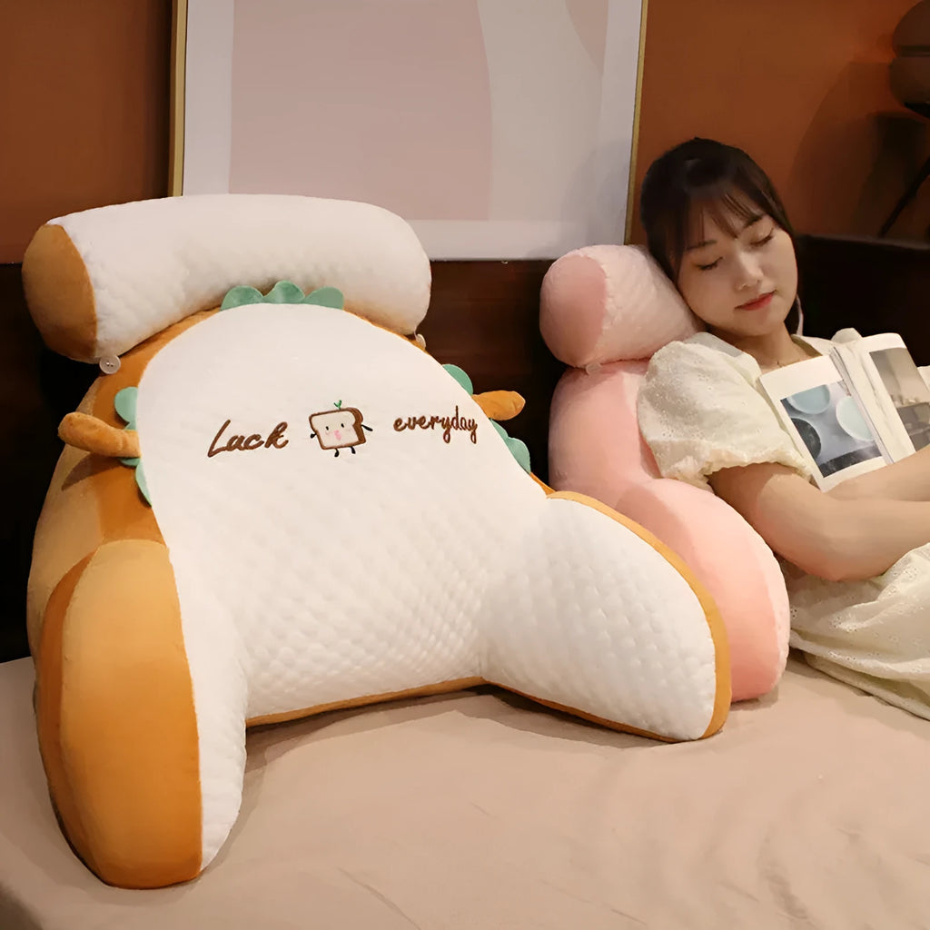 Grey triangle-shaped reading pillow with embroidery on a chair, showing its ergonomic back support shape.