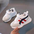 Children's white casual sneaker with Velcro strap and rubber sole on a neutral background.