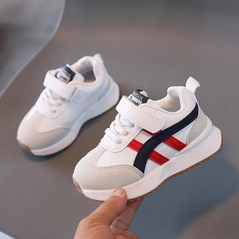 Children's white casual sneaker with Velcro strap and rubber sole on a neutral background.