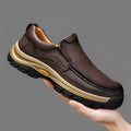 Men's black leather hiking shoes with thick rubber soles and round toe on a rocky outdoor path.