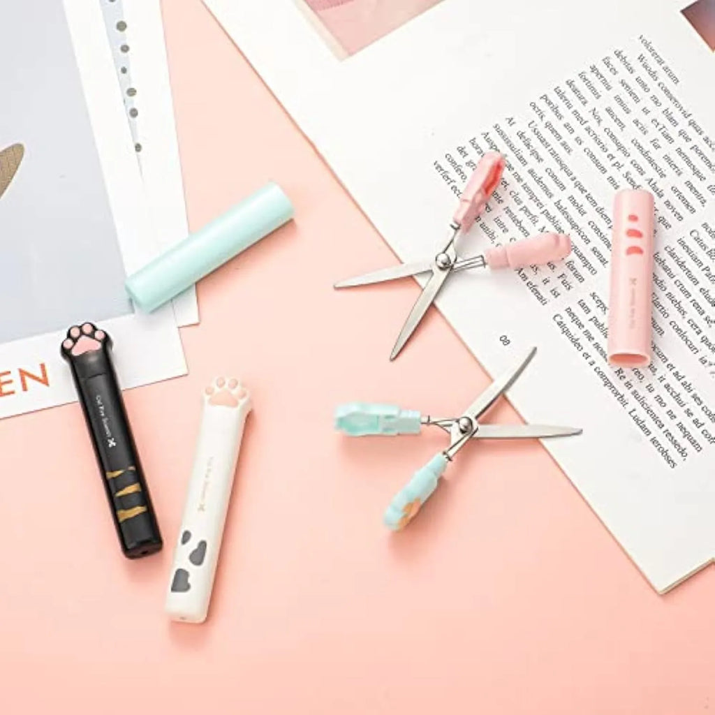 Set of four mini folding scissors with cat paw handles in pink, white, black, and blue colours, shown closed.