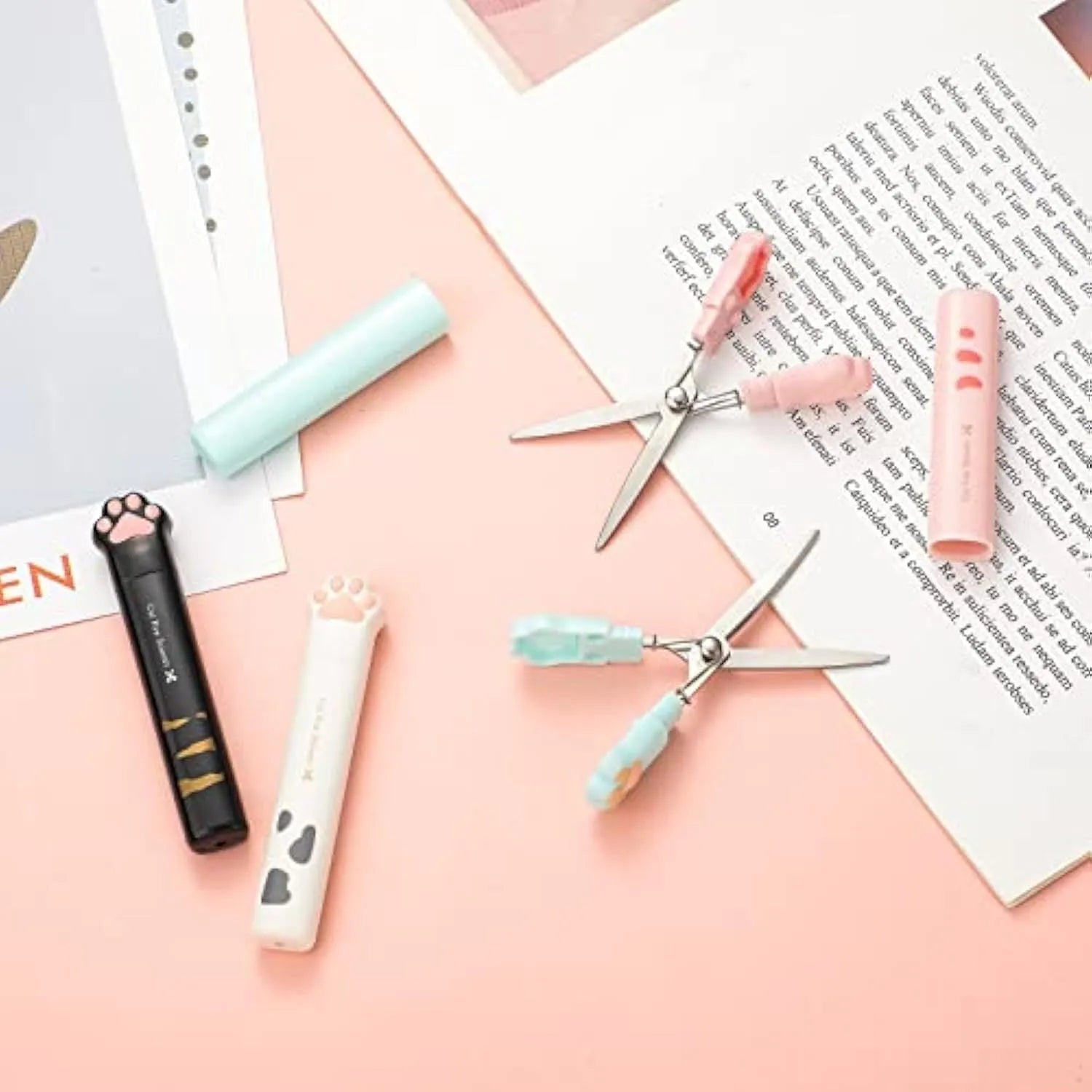 Set of four mini folding scissors with cat paw handles in pink, white, black, and blue colours, shown closed.