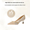 Women's champagne satin high heel wedding shoes with rhinestone decoration on a white background.