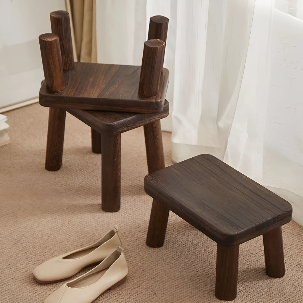 Distressed solid wood shoe stool with bracket legs in a living room setting.