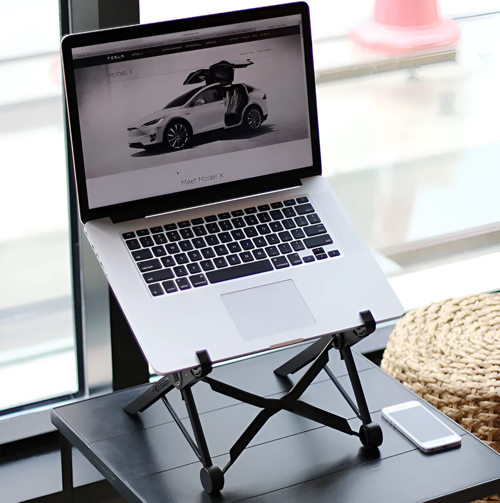 Black folding portable laptop stand made of reinforced nylon, shown folded to its compact size.