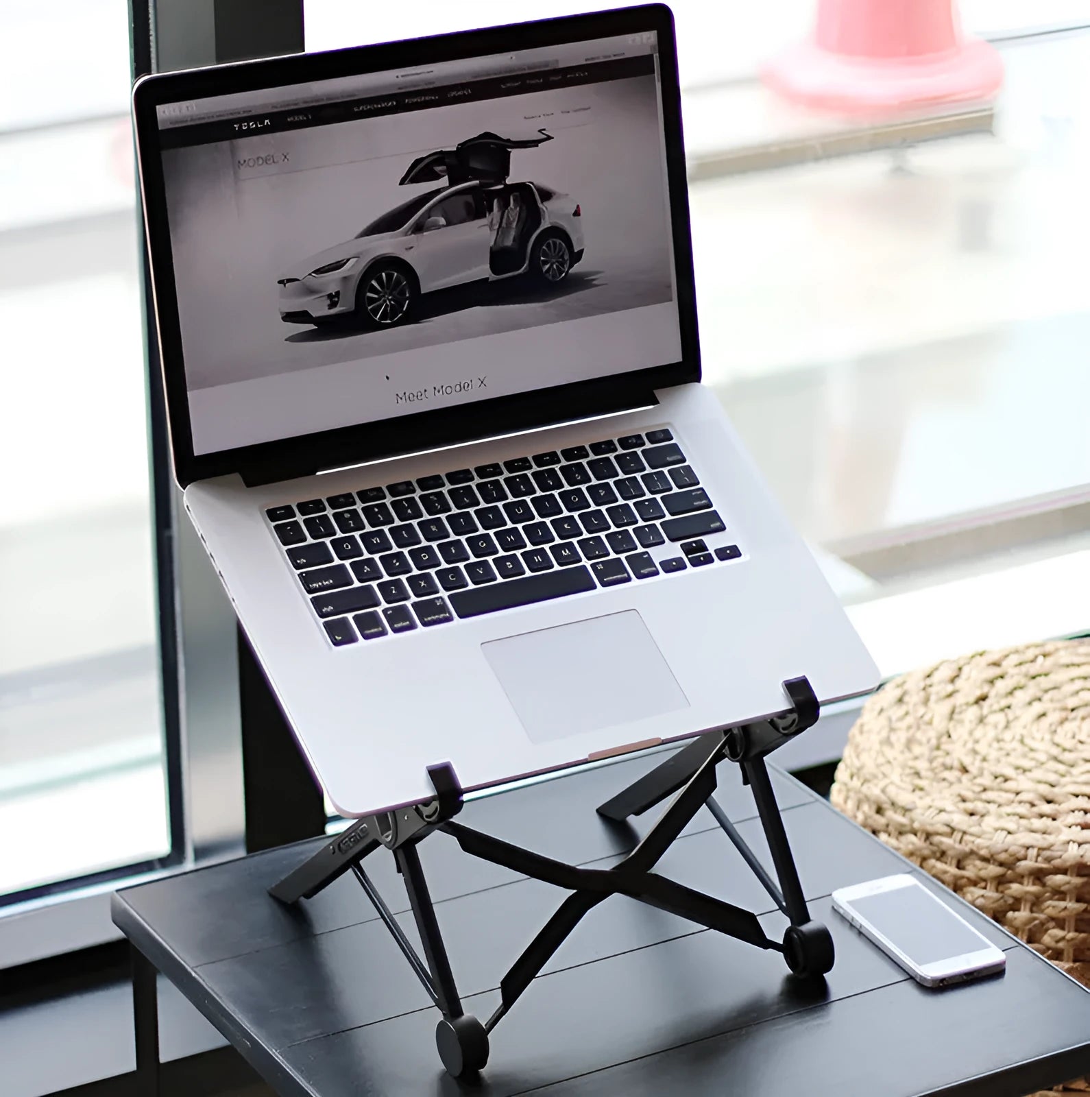 Black folding portable laptop stand made of reinforced nylon, shown folded to its compact size.