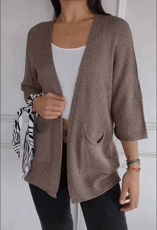 Women's longline waffle-textured cardigan coat in army green, showing pocket detail and nine-quarter sleeve length.