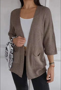 Women's longline waffle-textured cardigan coat in army green, showing pocket detail and nine-quarter sleeve length.