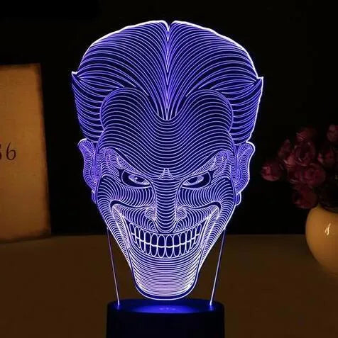 A 3D acrylic LED lamp with a square base, displaying one of its seven colour options on a desk.