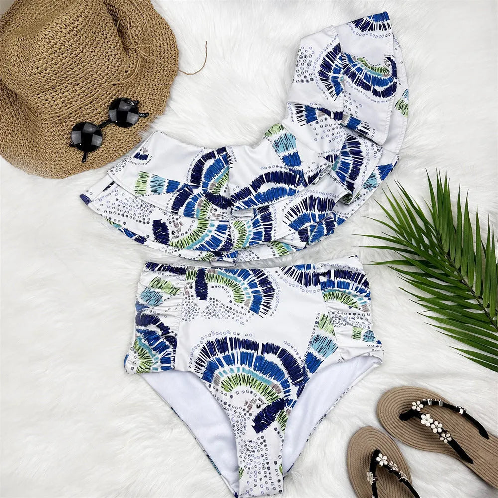 White women's one shoulder swimsuit with a layered lotus leaf skirt and a thigh high split.