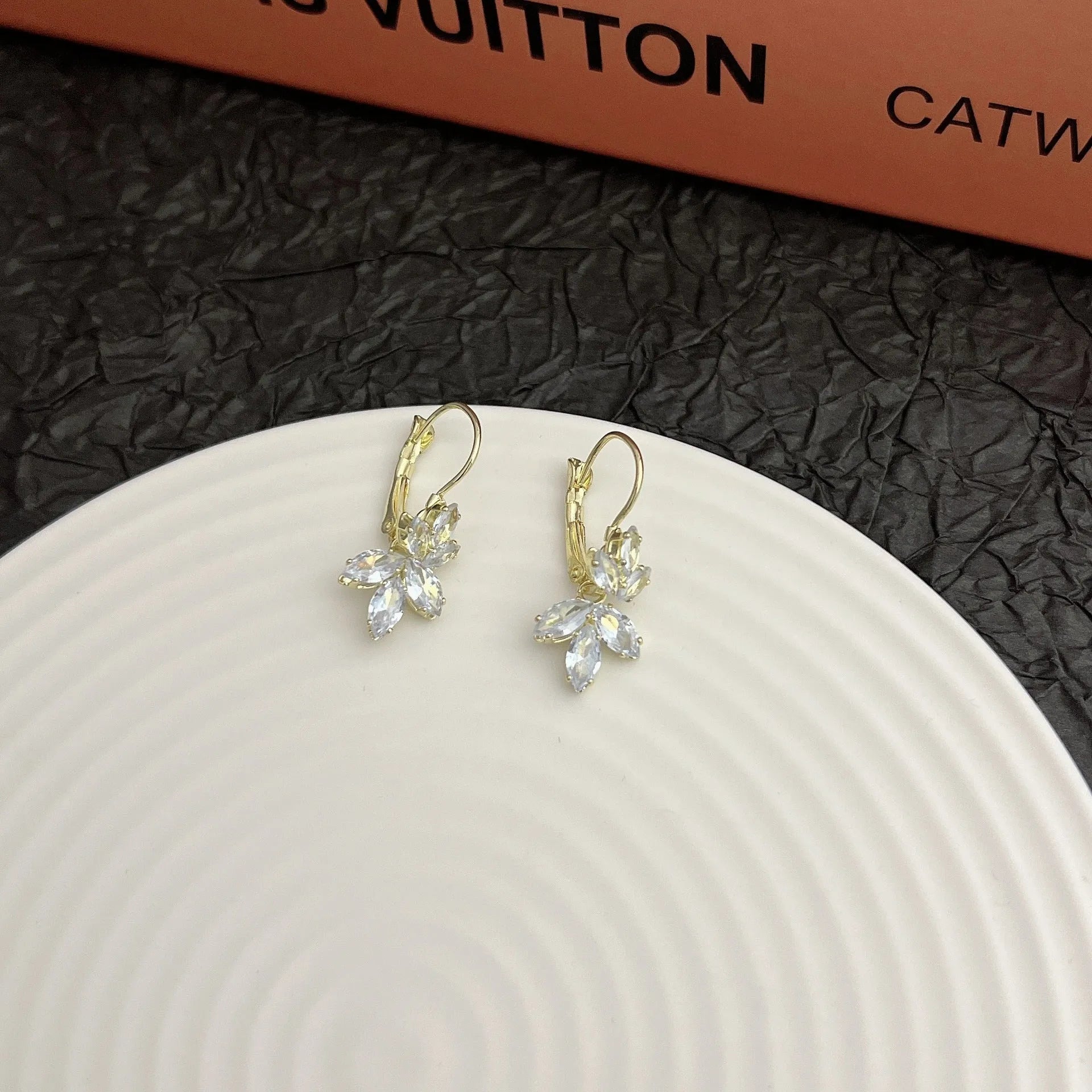 Women's platinum colour leaf earrings with inlaid zircon detailing on alloy background