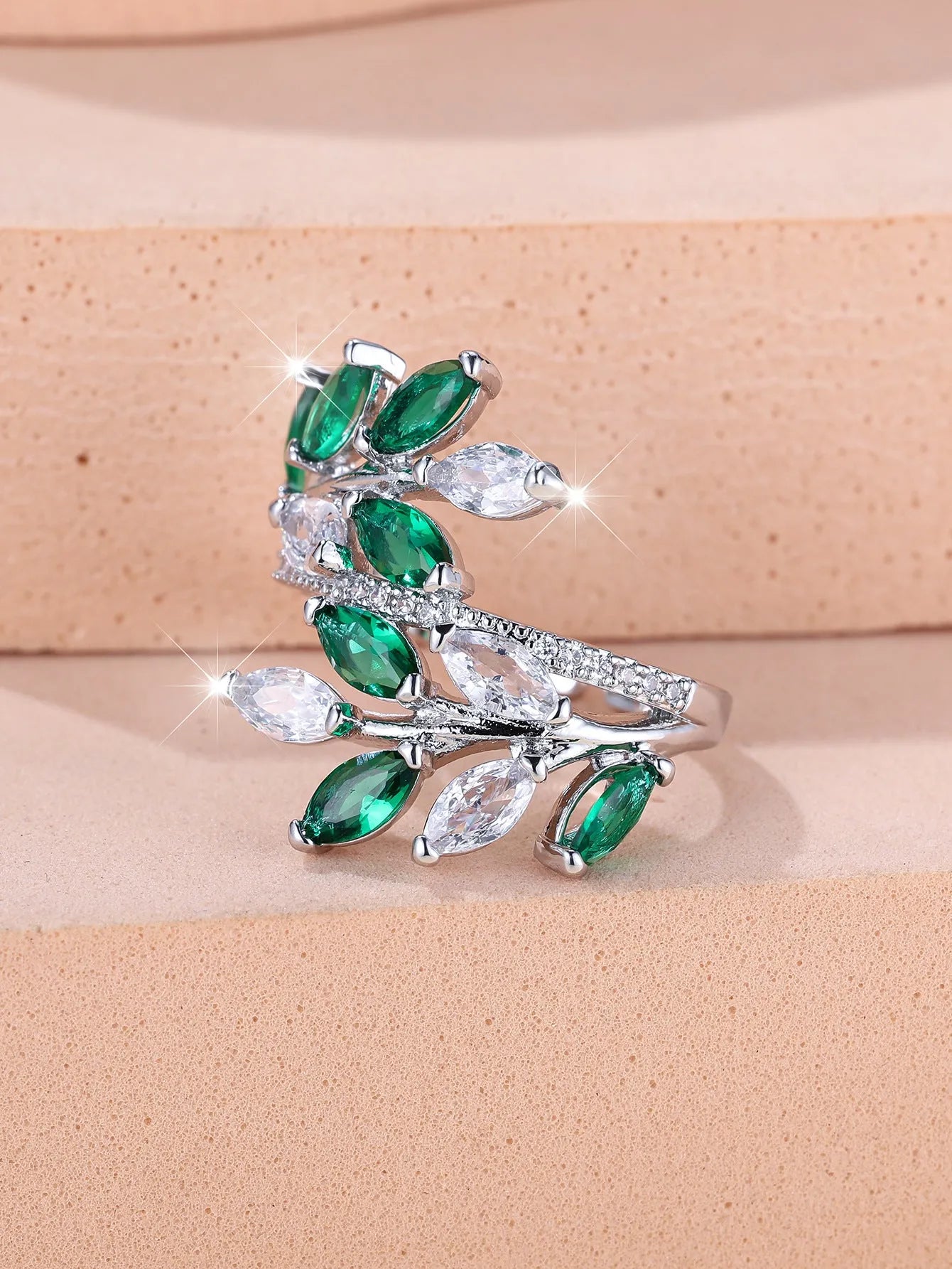 Adjustable copper leaf design ring with sparkling zircon stones on a model's finger.