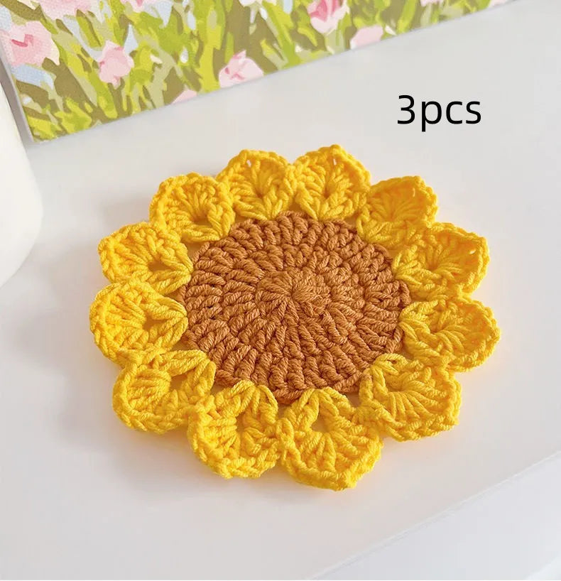 Hand-woven wool coaster with floral pattern on a wooden table.