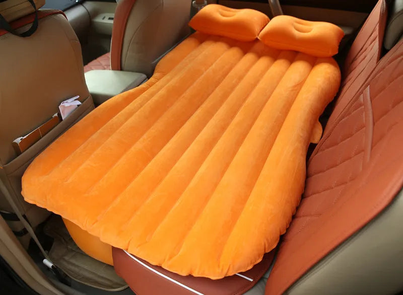 Inflatable car bed with flocked surface and two pillows, shown inside a five-seater vehicle.