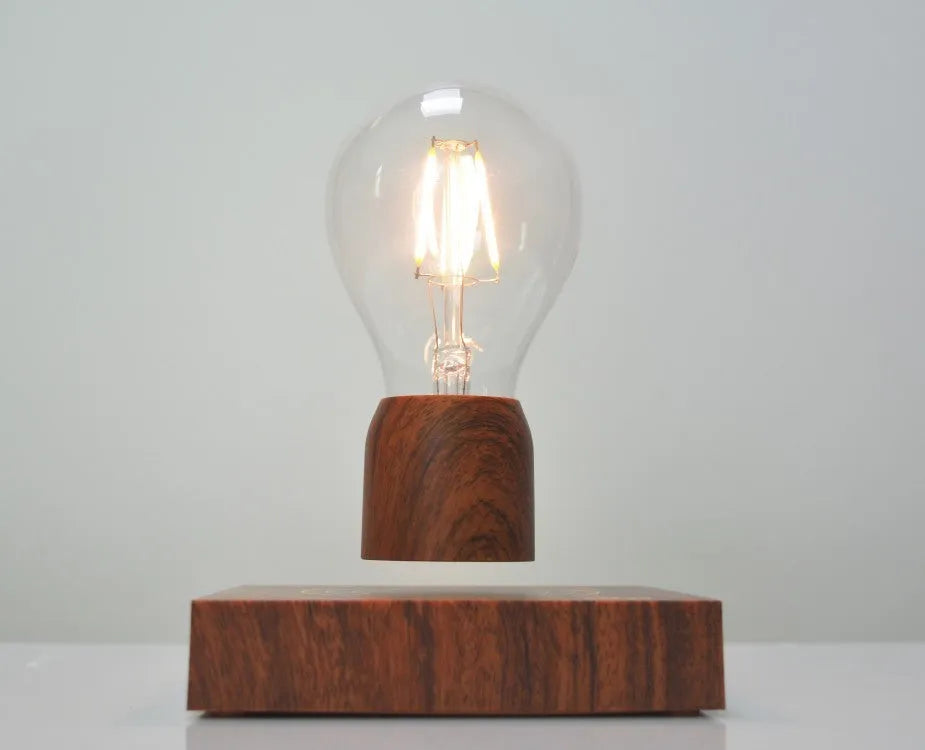 Magnetic levitation floating LED light bulb above an imitation wood base.