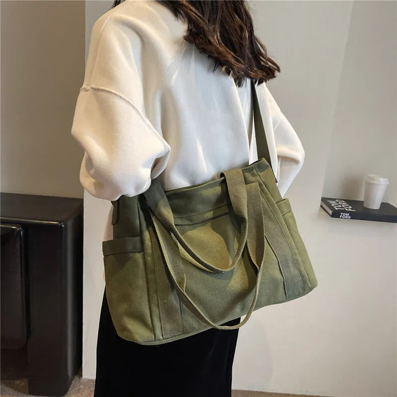 Polyester shoulder tote bag in solid colour with external sandwich pocket and internal phone pouch.