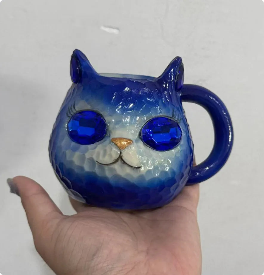 American-style resin ornament of a cat holding a crystal Earth globe in blue, green, pink, or purple.