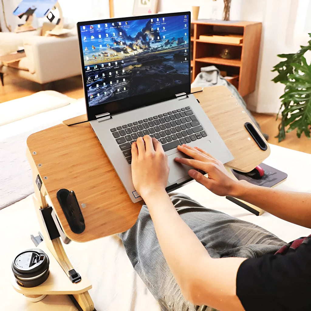 White wooden folding laptop table with adjustable angle, positioned on a bed.