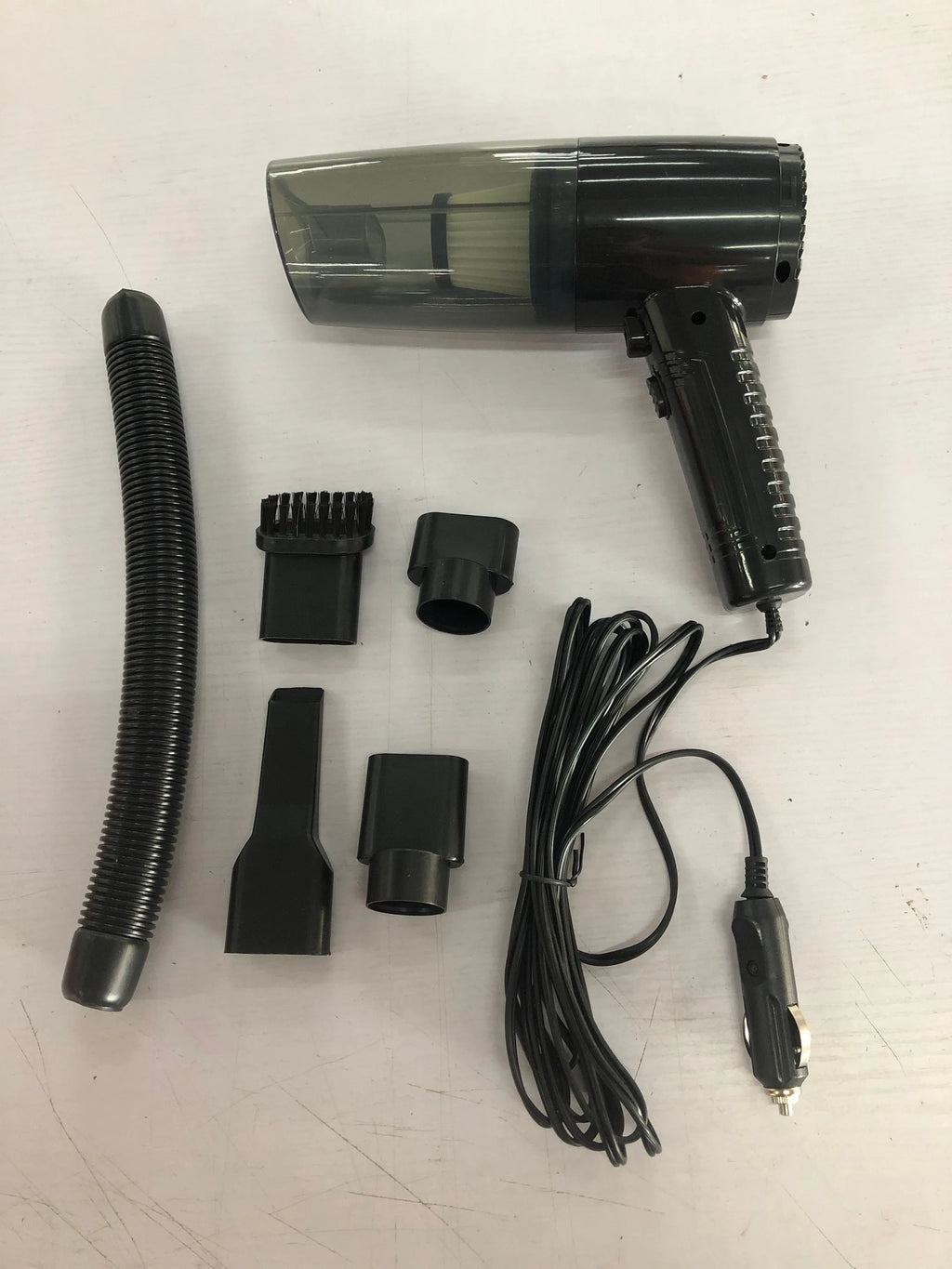 Black and white car vacuum cleaner with multiple accessory heads and extended power cord
