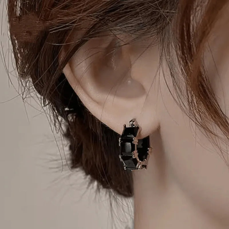 Geometric U-shaped gold earrings with a round black crystal zircon stone.