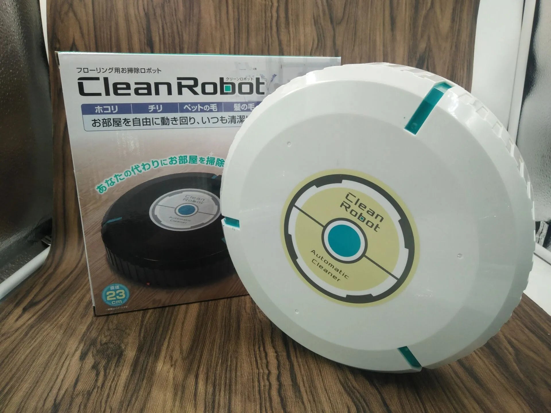 Black or white AC-powered robot vacuum cleaner on a wooden floor.