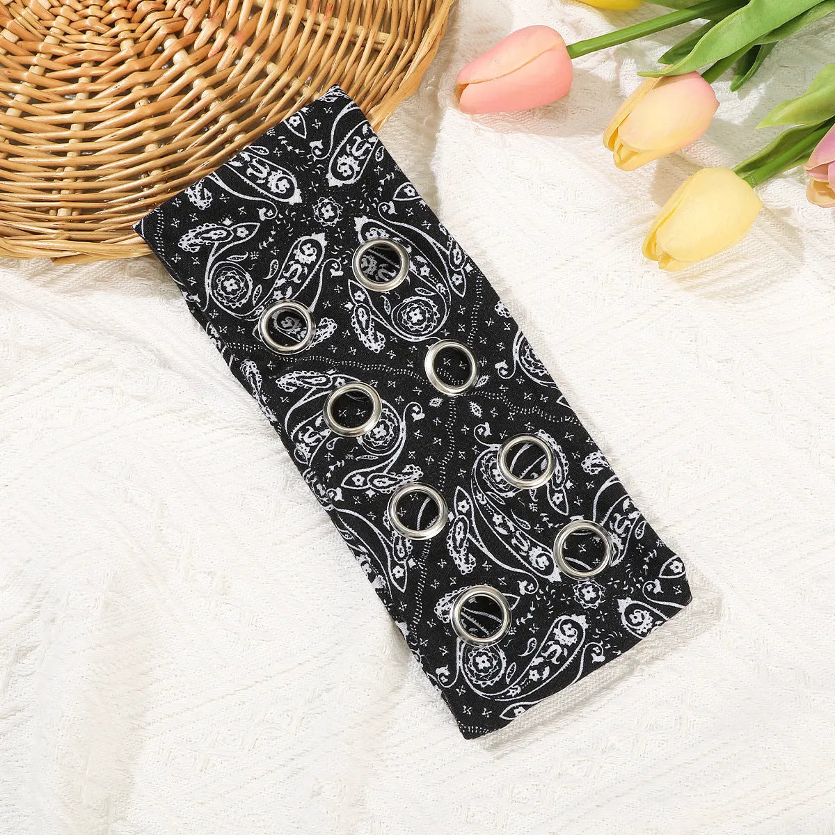A black polyester exercise hair band with a hollow metal decorative centrepiece.