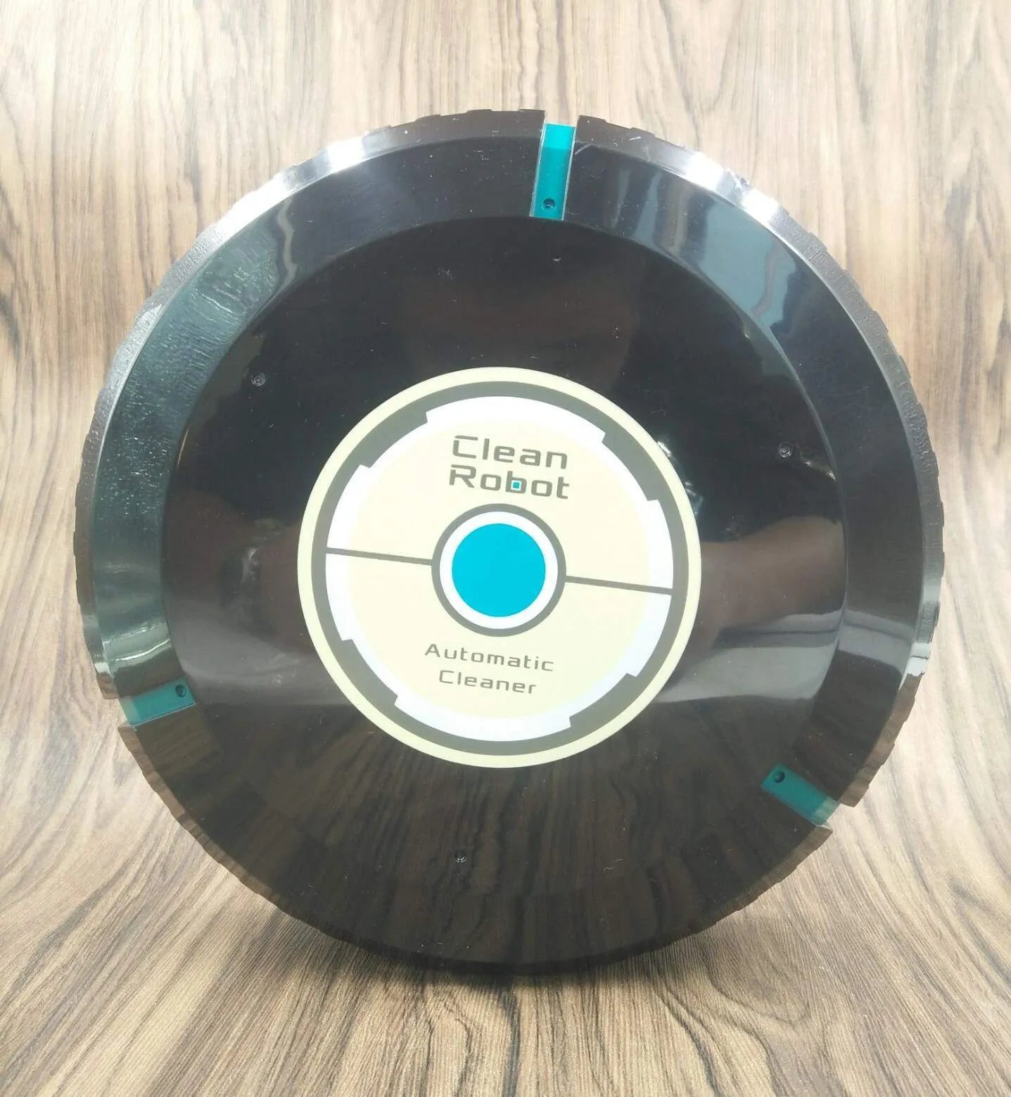 Black or white AC-powered robot vacuum cleaner on a wooden floor.