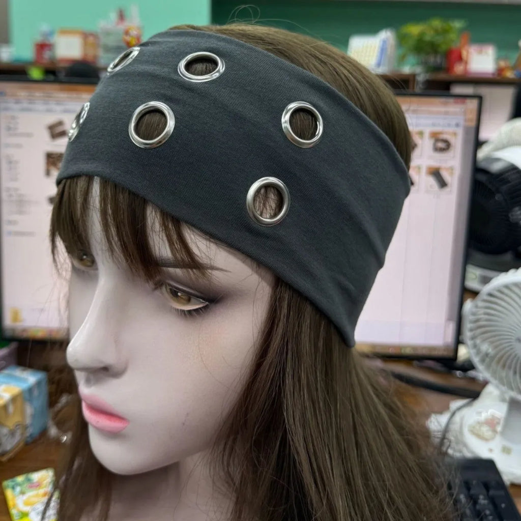 A black polyester exercise hair band with a hollow metal decorative centrepiece.