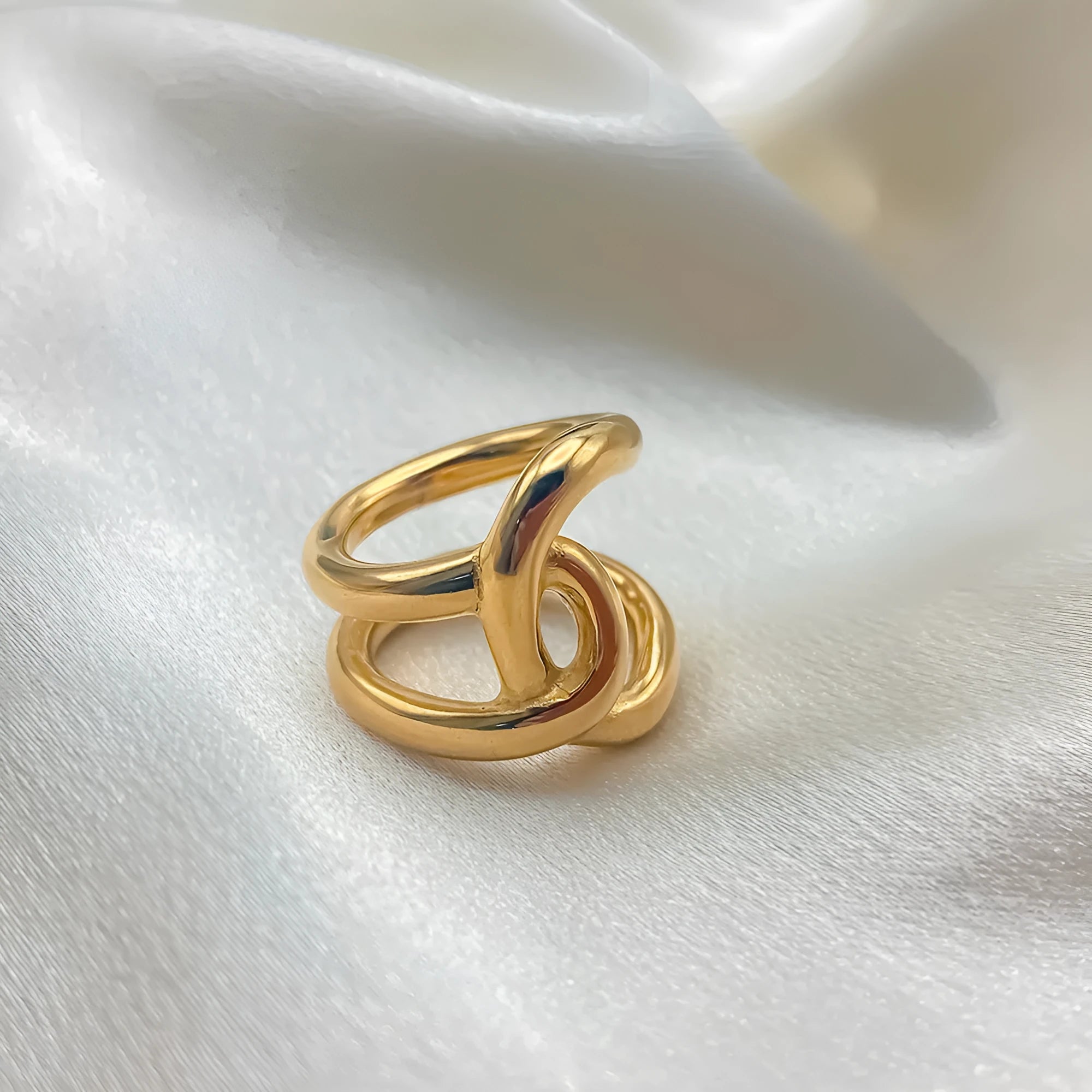Women's stainless steel adjustable knotted ring in gold or steel colour on a U-shape geometric band.